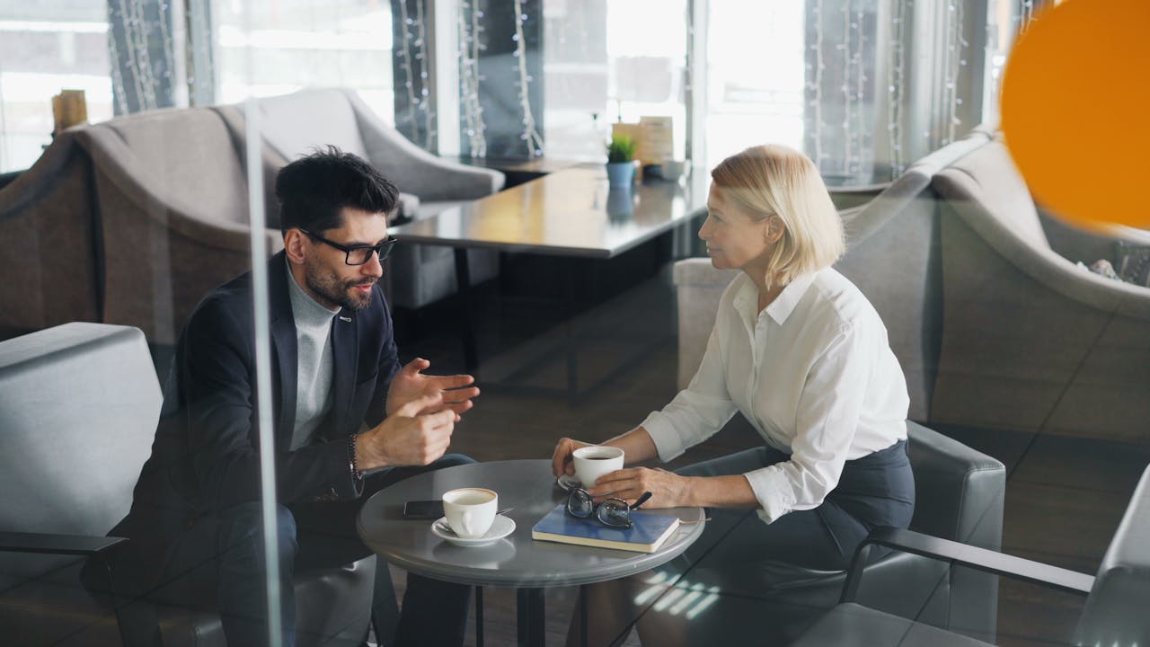 Business professionals in a discussion over coffee in a modern office setting.