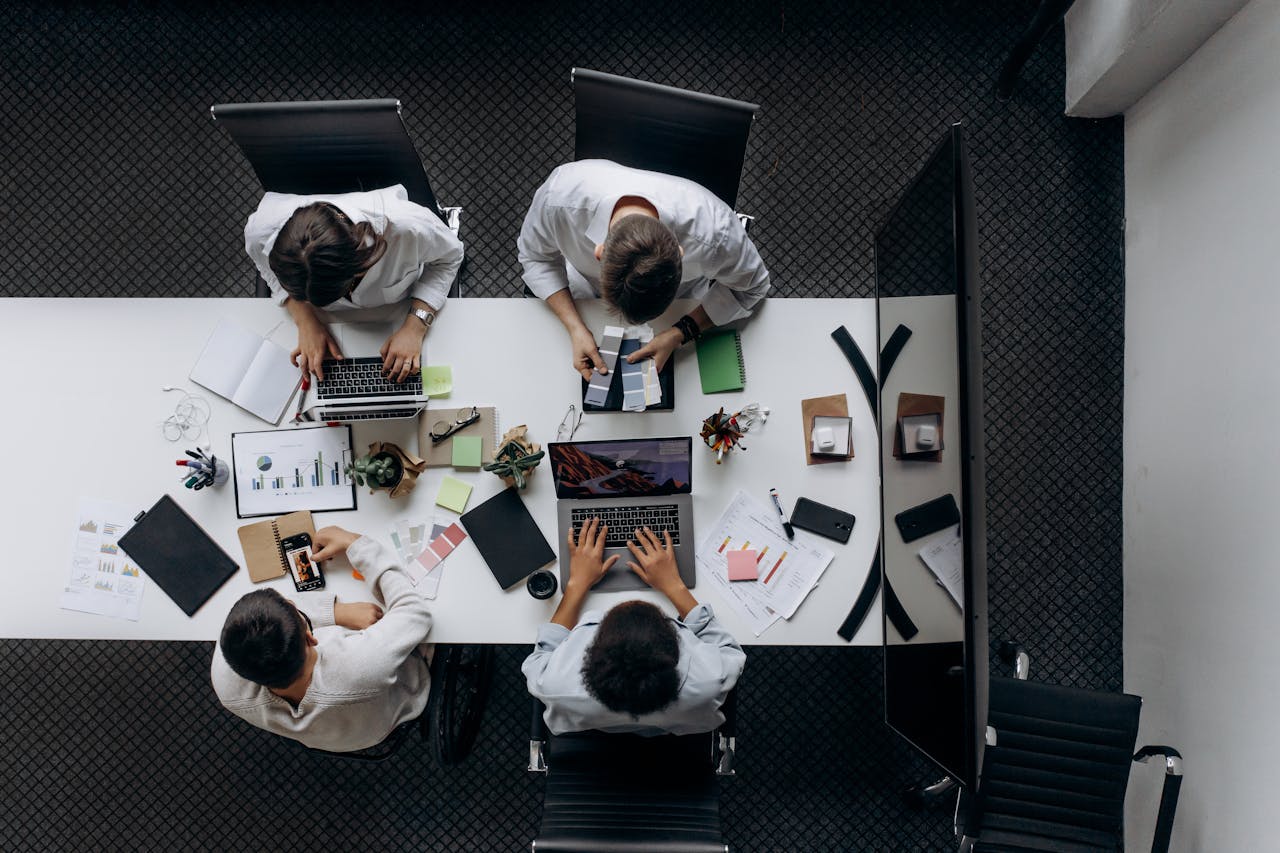 Teamwork in modern office with laptops, charts, and electronic devices from above.